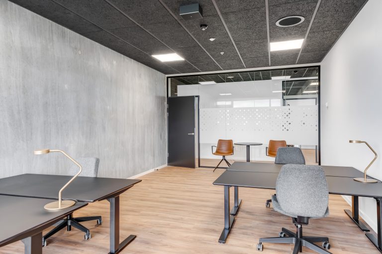 Office H5.18 with desks, concrete wall and glass wall to the corridor