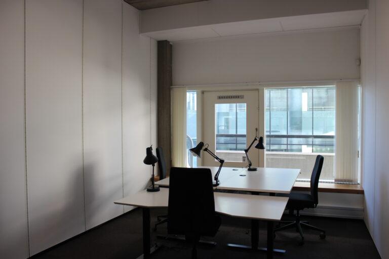 Office with four workstations, desk lamps and a window front