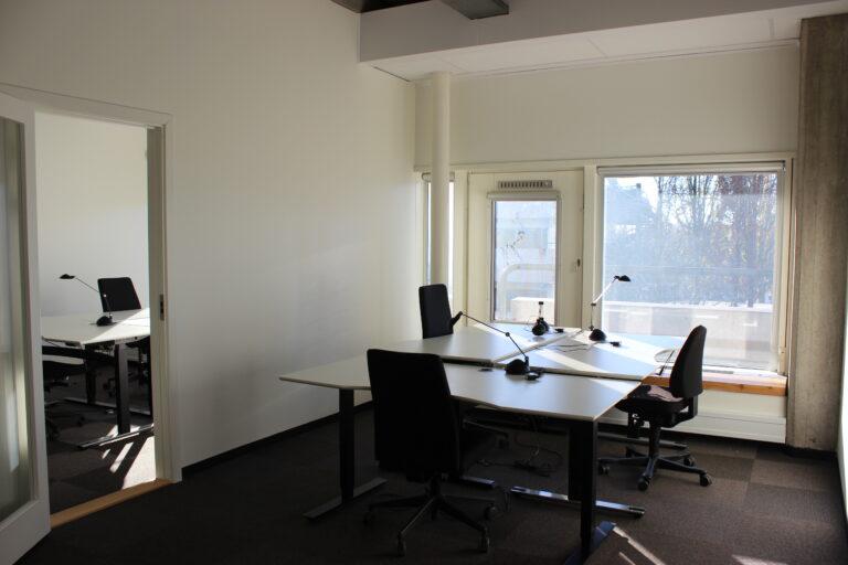 Office with four workstations and a doorway to the adjoining room